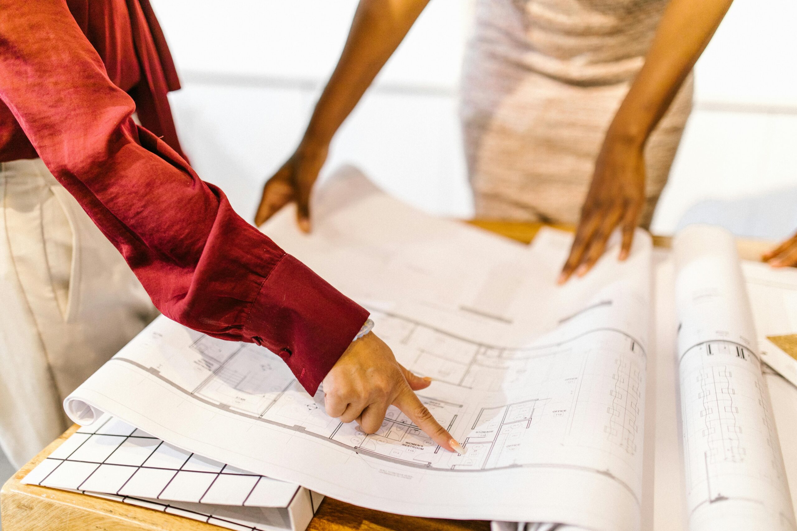 Two women collaborate on architectural plans in a modern office setting.